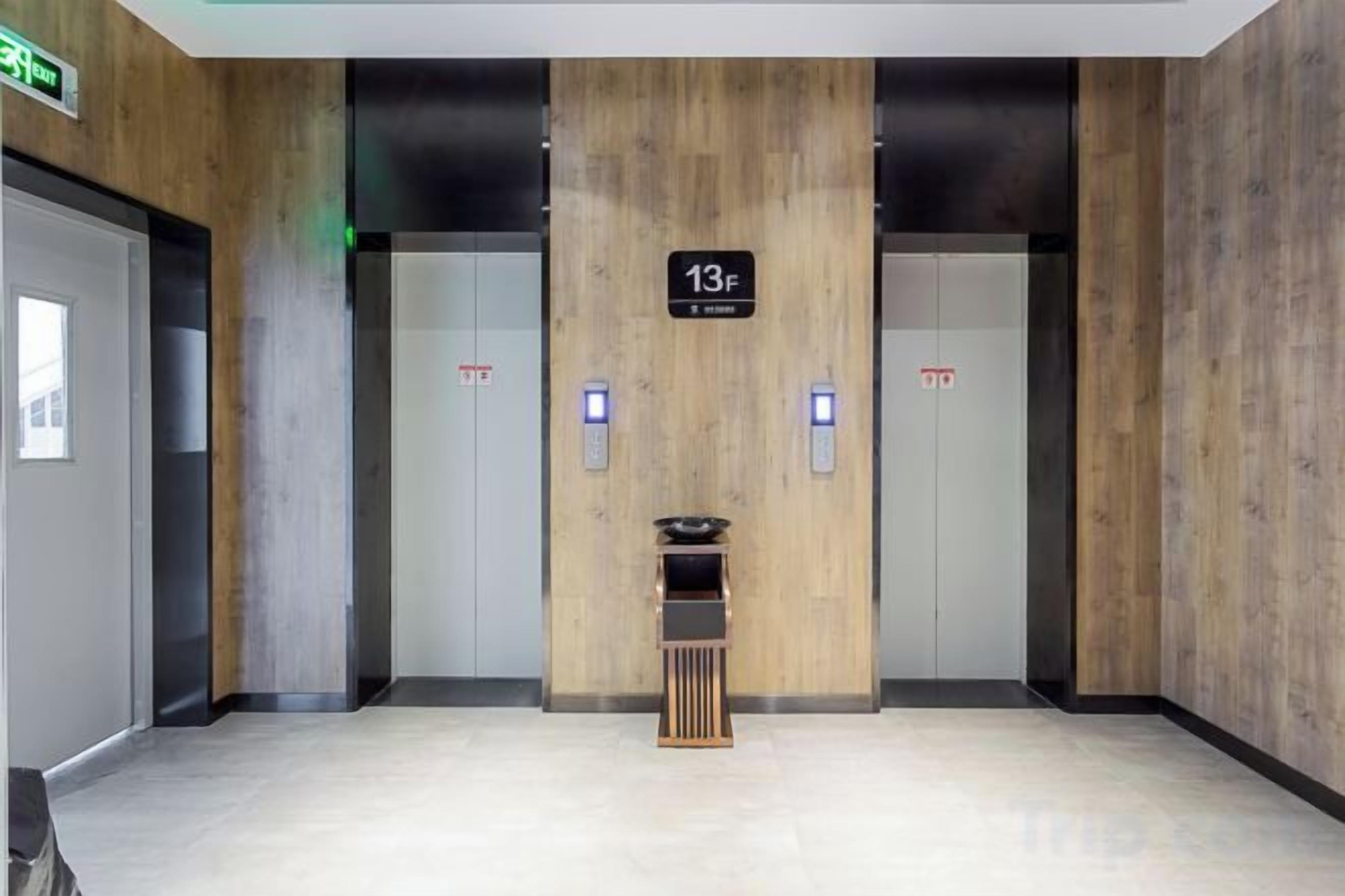 An elevator with a sign indicating floor 13F, two emergency buttons, and a small shelf with items.