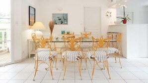 A dining area with a glass table and chairs, a lamp, and artwork on the walls.
