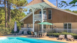 A two-story house with a pool, outdoor furniture, and a covered patio area.