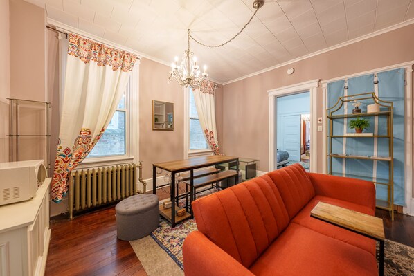 Ein Wohnzimmer mit einem roten Sofa, einem Holztisch, einer Kandelaber und einem Bücherregal.