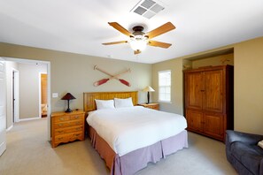 Ein Schlafzimmer mit einem Bett, Nachttischen aus Holz, einem Kleiderschrank und einem Deckenventilator.