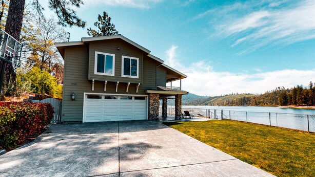 Une maison à deux étages avec un garage, une véranda et une vue sur un lac.