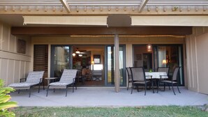Eine überdachte Terrasse mit Außenmöbeln, ein Glastür-Eingang zu einem Essbereich und ein Deckenventilator.