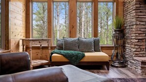 A cozy cabin interior with a sofa, a small table, and a stone fireplace. - Sleeps 28! • Loaded w/ Amenities • Mins from Lake! (Broken Bow)