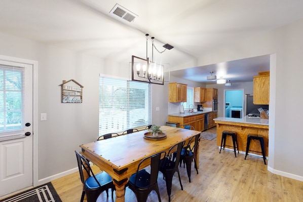 A spacious kitchen with a wooden dining table, bar stools, and modern appliances.