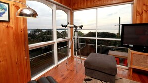 A wooden-paneled room with large windows, a tripod, and a television.