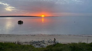 A calm lake at sunset with a small island and a distant shoreline.