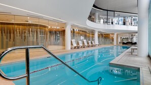 An indoor swimming pool with a modern design, lounge chairs, and a glass wall. - Riverside Views Melbourne - WiFi-Netflix (Docklands)