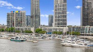 A marina with yachts and a cityscape of modern high-rise buildings. - Riverside Views Melbourne - WiFi-Netflix (Docklands)