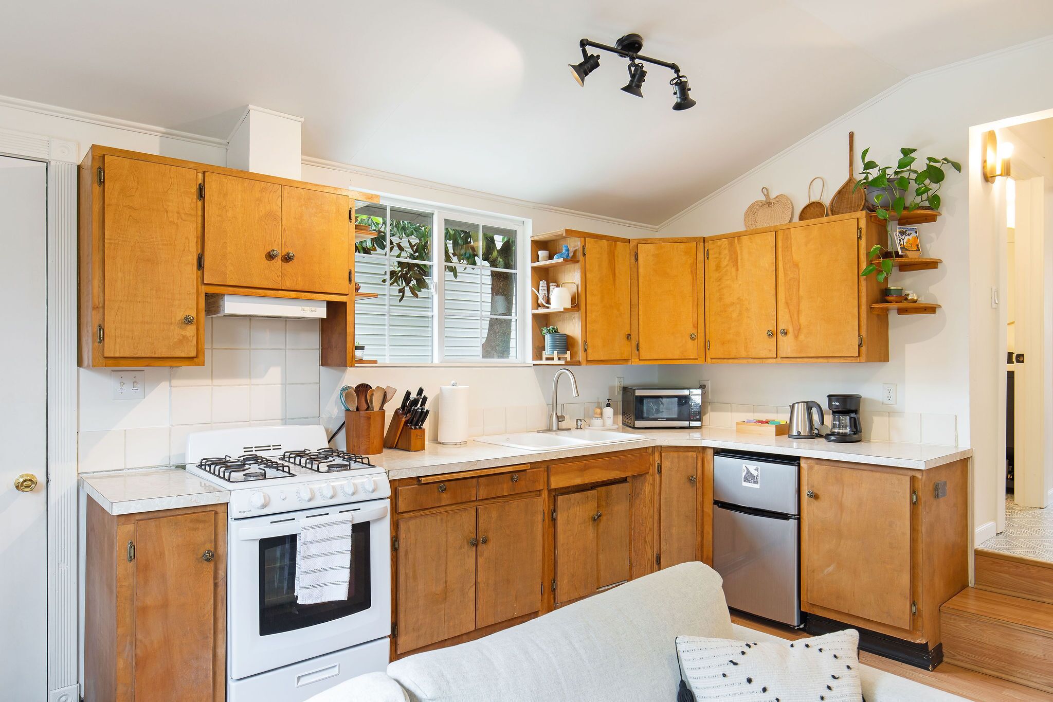 A kitchen with wooden cabinets, a stove, a microwave, and a sink.