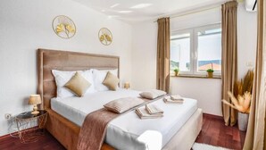 A hotel room with a large bed, a wooden headboard, a bedside table with a lamp, and a window with curtains.