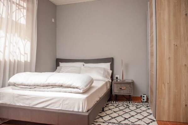 Une chambre à coucher avec un lit, une table de chevet et une armoire en bois.