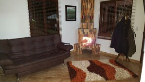 Una sala de estar con un sofá de cuero marrón, una chimenea y una alfombra estampada.