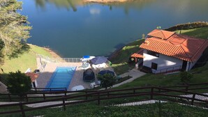 Una piscina con una tumbona, un área de juegos infantil y un edificio de techo rojo.