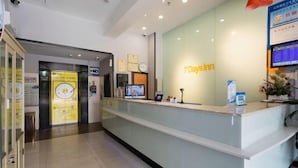 A reception desk with a glass partition, a clock, and a digital screen displaying information. - 7Days Inn Shenzhen Shajing Metro Station public square (Shenzhen)