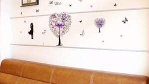 A room with a brown leather sofa, a wall decorated with a heart-shaped floral design, and butterfly decals. - 7Days Inn Shenzhen Shajing Metro Station public square (Shenzhen)