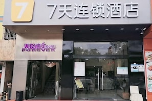 A hotel entrance with a sign indicating it is the 7th hotel in a chain.