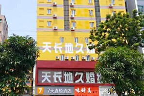 A multi-story building with a prominent yellow facade and signage indicating a hotel. - 7Days Inn Shenzhen Shajing Metro Station public square (Shenzhen)