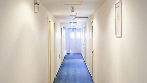 A long, narrow hallway with doors on both sides, leading to a bright room at the end. - 7Days Inn Shenzhen Shajing Metro Station public square (Shenzhen)