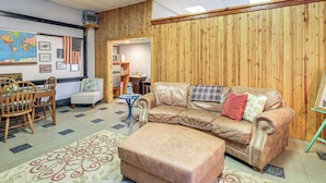 A living room with a leather sofa, a coffee table, a patterned rug, a wooden wall, and a map on the wall. - Direct Warrior Trail Access! Ultimate ATV Getaway (Gary)