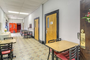 A hallway with tables and chairs, doors with signs, and a patterned floor. - Direct Warrior Trail Access! Ultimate ATV Getaway (Gary)