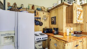 Una cocina con un refrigerador, estufa y horno blancos, armarios de madera, y diversos utensilios y electrodomésticos de cocina.