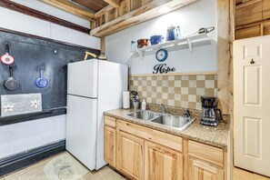 A kitchen with a refrigerator, sink, coffee maker, and wooden cabinets.