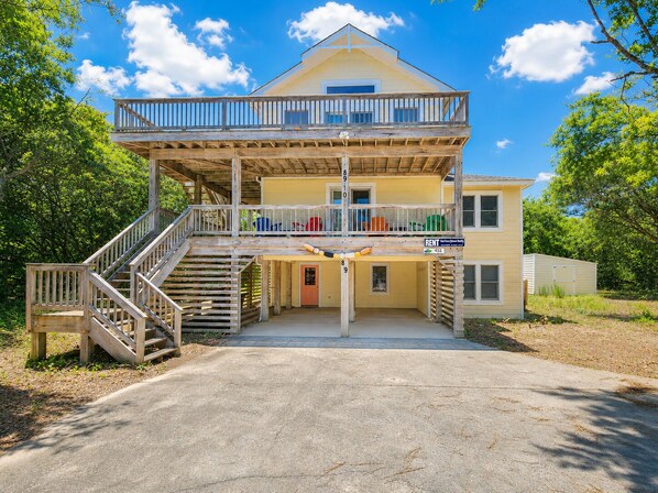 A two-story building with a balcony, a staircase, and a sign indicating it is for rent. - 🦀 Knot Too Crabby - 5 BR home w/Private Pool & Hot Tub 🦀 (Southern Shores)