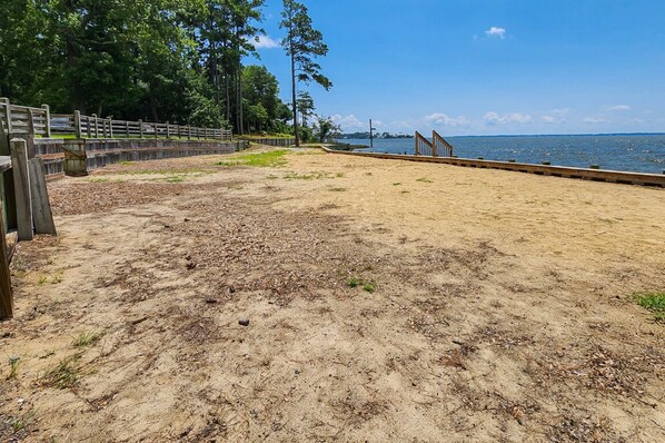 A sandy beach area with a wooden fence and a wooden walkway leading to the water. - 🦀 Knot Too Crabby - 5 BR home w/Private Pool & Hot Tub 🦀 (Southern Shores)