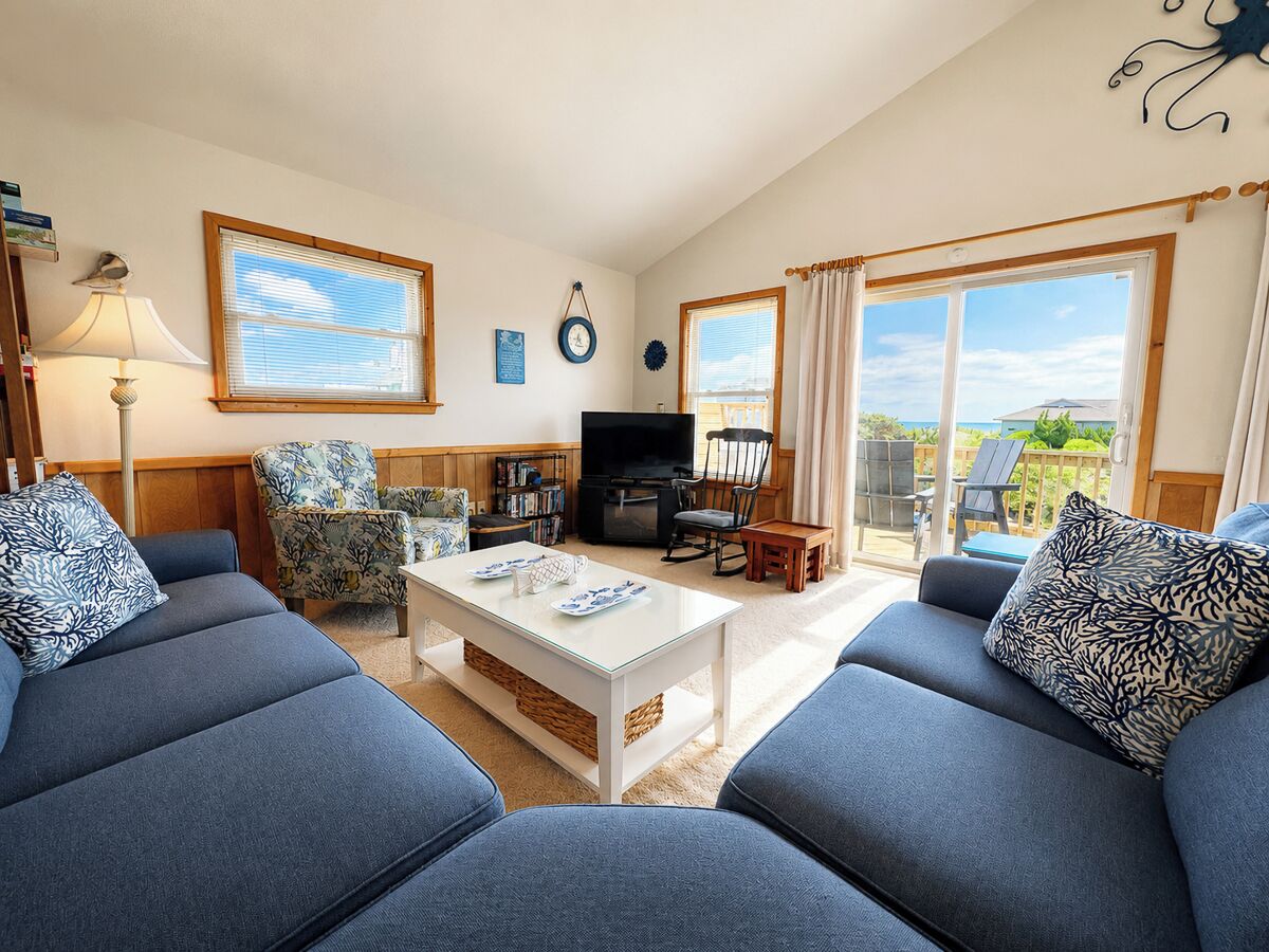 A living room with a sofa set, a coffee table, a TV, and a bookshelf.