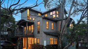 Une maison à plusieurs étages dotée d’un balcon, de fondations en pierre et d’une allée.