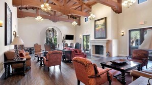 Un vaste salon doté de hauts plafonds, de poutres en bois et d’une cheminée. On y trouve plusieurs coins salon avec des fauteuils confortables et une table basse.
