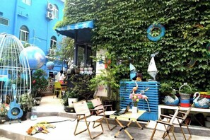 An outdoor seating area with chairs and tables, surrounded by greenery and decorative items. - Yimu Huatian Inn (Shenzhen)