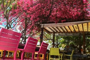A covered outdoor seating area with colorful chairs and a pergola structure. - Yimu Huatian Inn (Shenzhen)