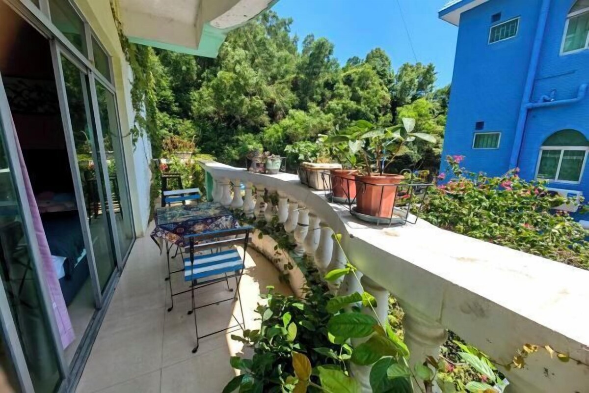 A balcony with potted plants, a table, and chairs.