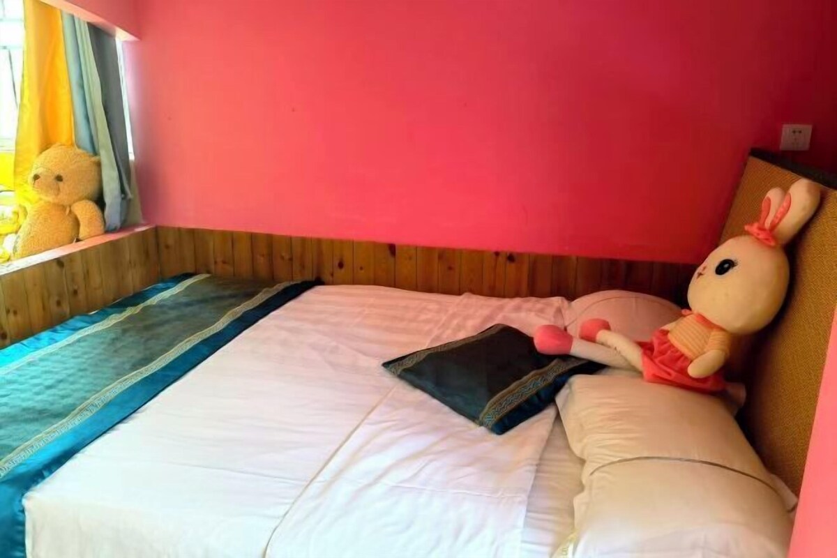 A bed with white bedding, a pink wall, and a window with curtains.