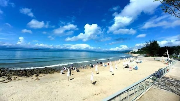 A beach with a clear sky, sandy shore, and umbrellas. - Yimu Huatian Inn (Shenzhen)