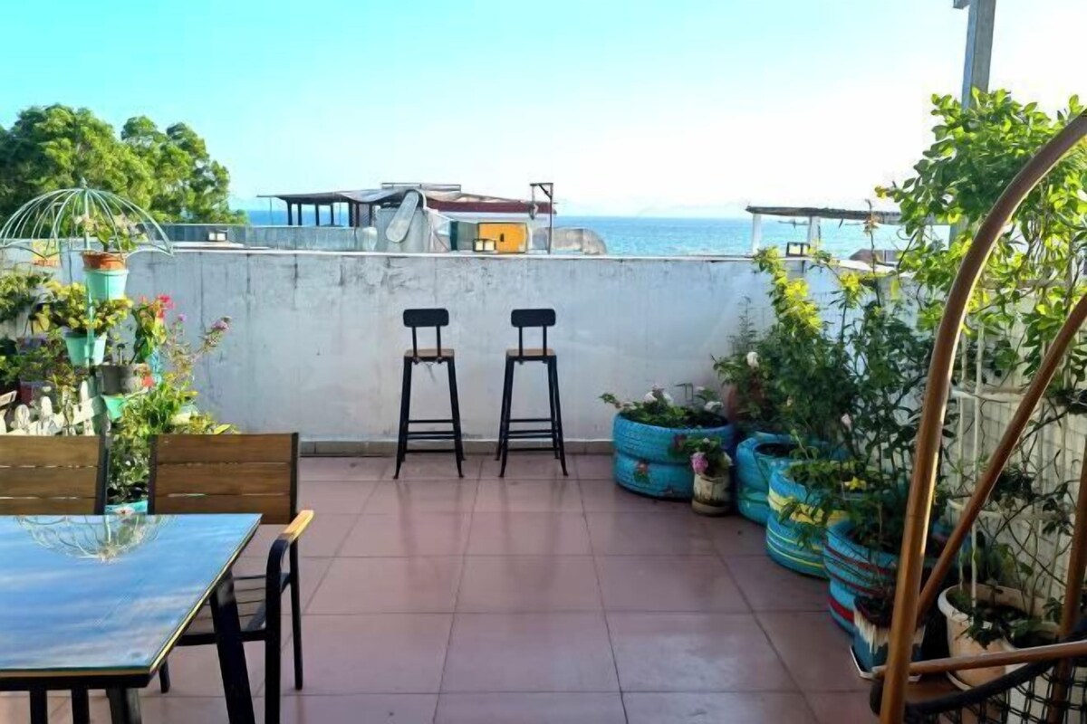 A patio with two stools, a table, and potted plants.