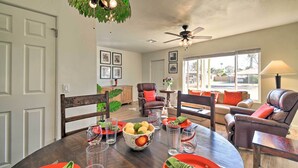 A dining area with a round table set for four, surrounded by chairs. There is a ceiling fan above the table and a large window providing natural light. - Pet-Friendly Phoenix Home: Breezeway & Fenced Yard (Phoenix)