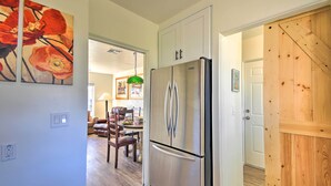 A modern kitchen with a stainless steel refrigerator, wooden cabinets, and a dining area with a table and chairs. - Pet-Friendly Phoenix Home: Breezeway & Fenced Yard (Phoenix)