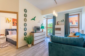 A modern living room with a sofa, a TV, a side table, and a bed. There are decorative items on the wall and a window with curtains. - Vacation apartment by the sea, vacation on the island of Usedom, Apartment TOWER 22 (Swinoujscie)