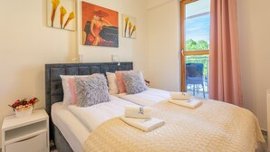 A neatly made bed with a fluffy pillow, a bedside table with a flower arrangement, and a window with curtains. - Vacation apartment by the sea, vacation on the island of Usedom, Apartment TOWER 22 (Swinoujscie)