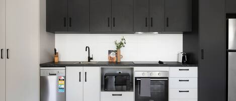 Een moderne keuken met zwarte kastjes, een vaatwasser, een magnetron, een oven en een koelkast.