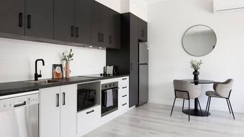 A modern kitchen with dark cabinets, a black countertop, and a round mirror on the wall.