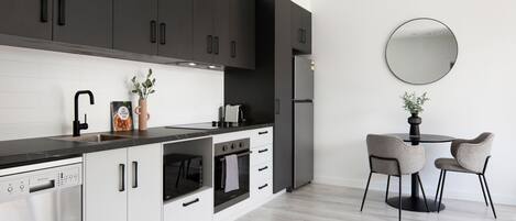Una cocina moderna con armarios oscuros, una encimera negra y un espejo redondo en la pared.