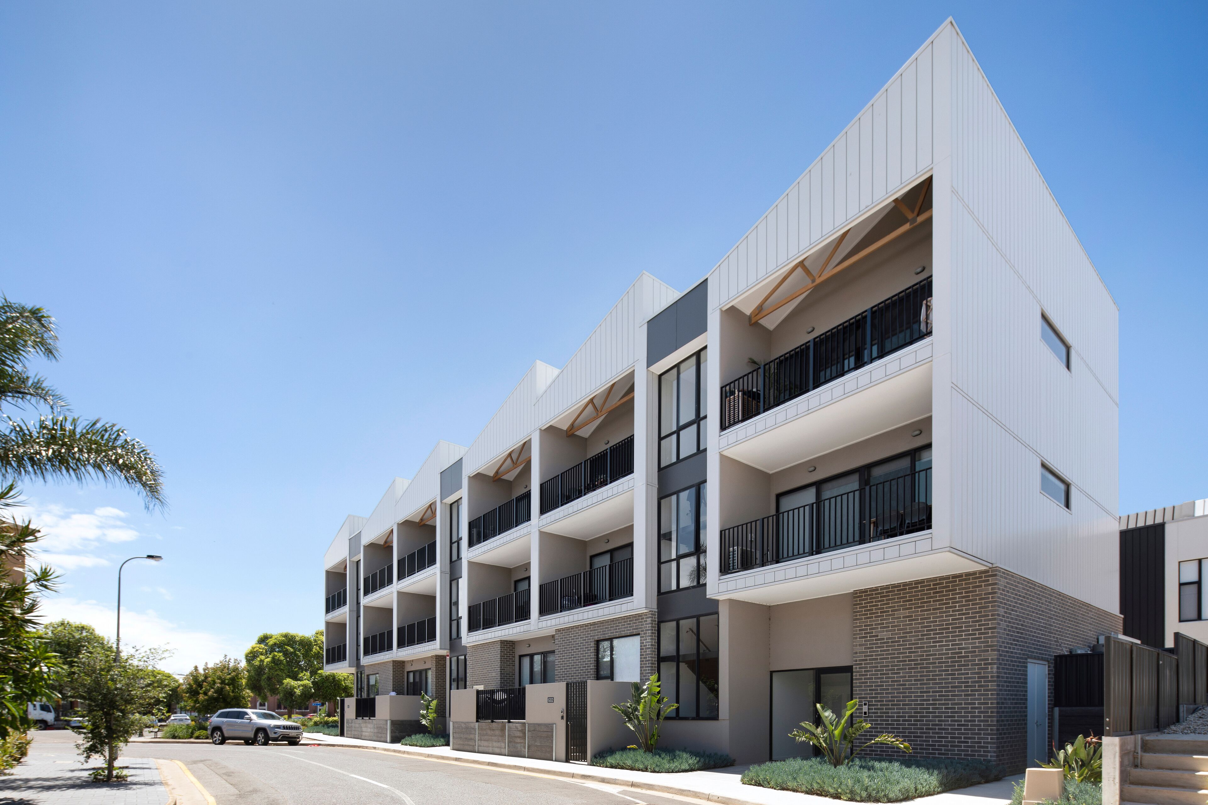 Un moderno edificio residencial de varios pisos con balcones y ventanas amplias.