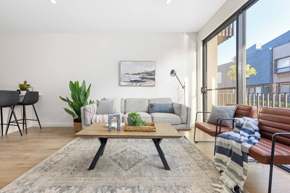 A modern living room with a sofa, a coffee table, and a large window.