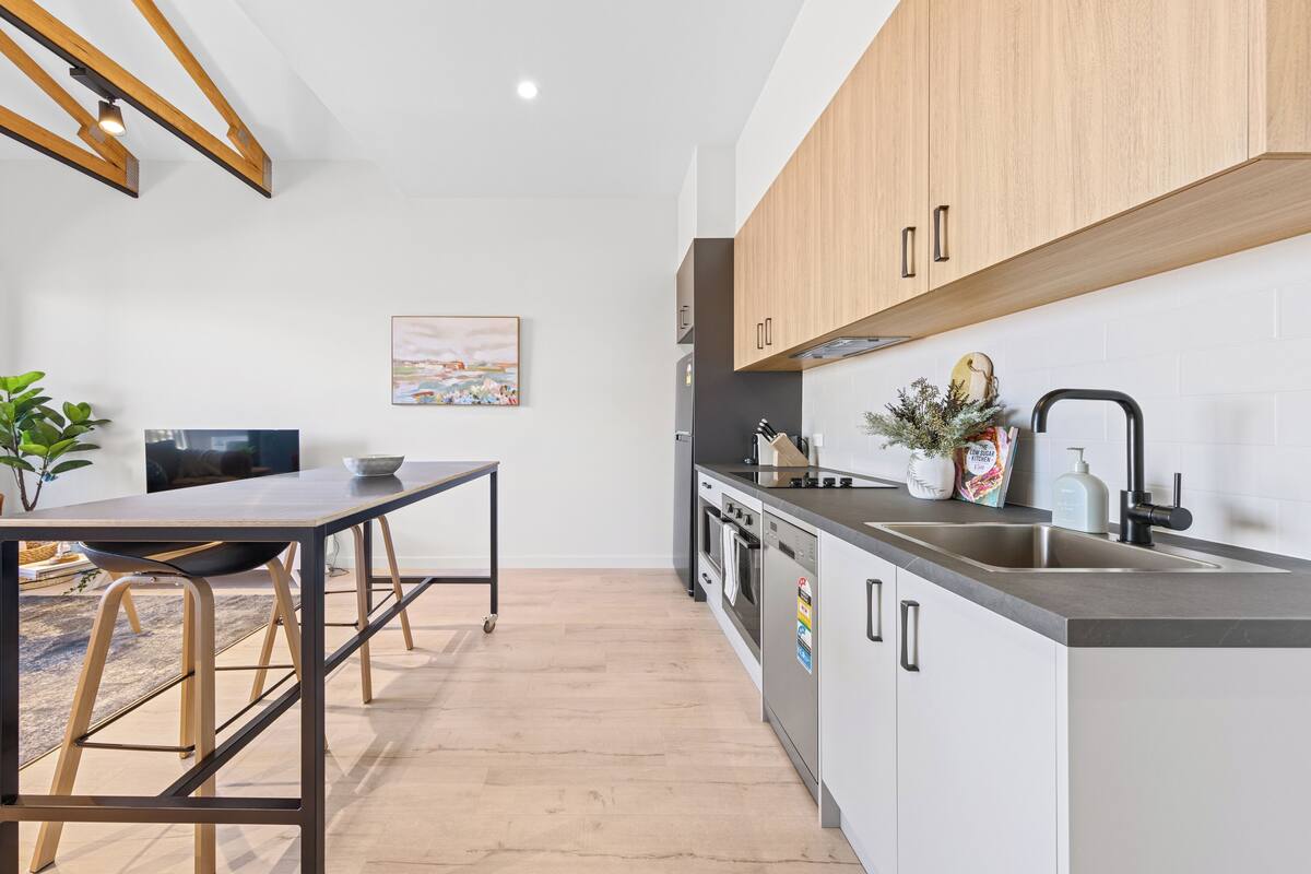 A modern kitchen with wooden cabinets, a stainless steel sink, and a built-in oven.