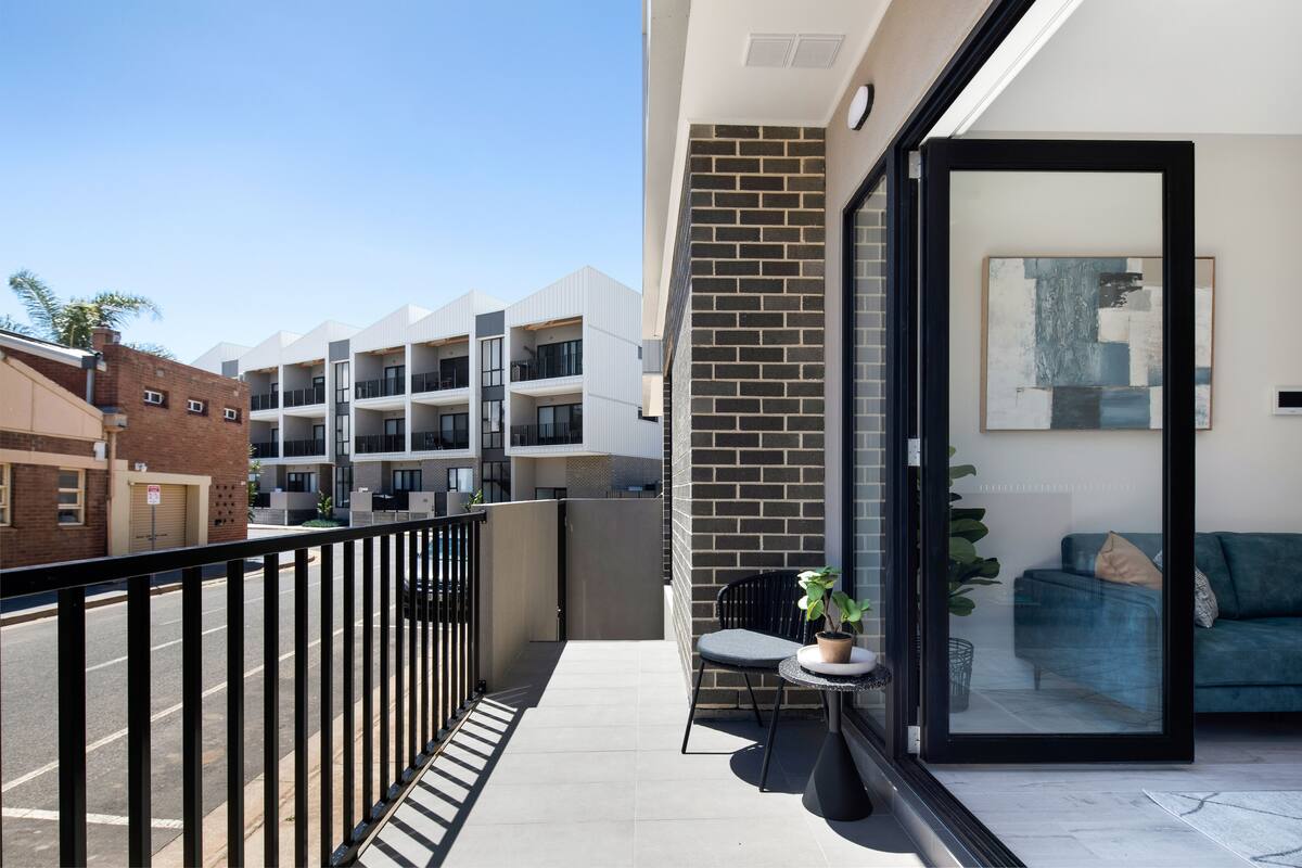 A balcony with a glass door, a small table with a chair, and a potted plant.