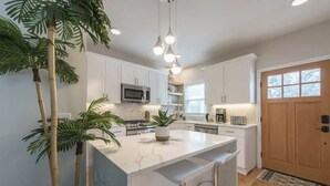A modern kitchen with white cabinets, a central island, and pendant lighting. - Airy Downtown 1BR w/ Parking (Princeton)